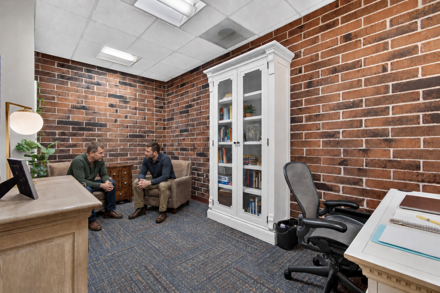 Two men talking in the brick-walled room at Genesis