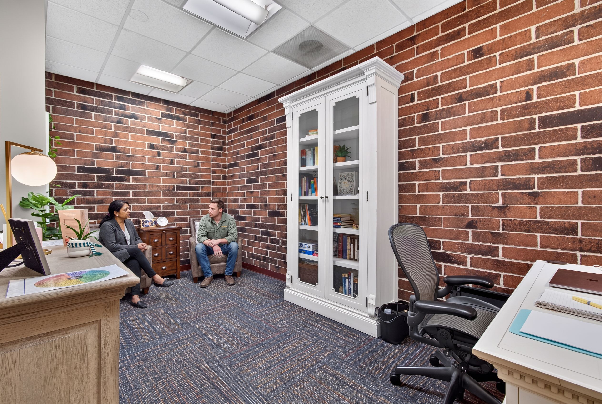 Two people talking quietly in a corner of the Genesis office