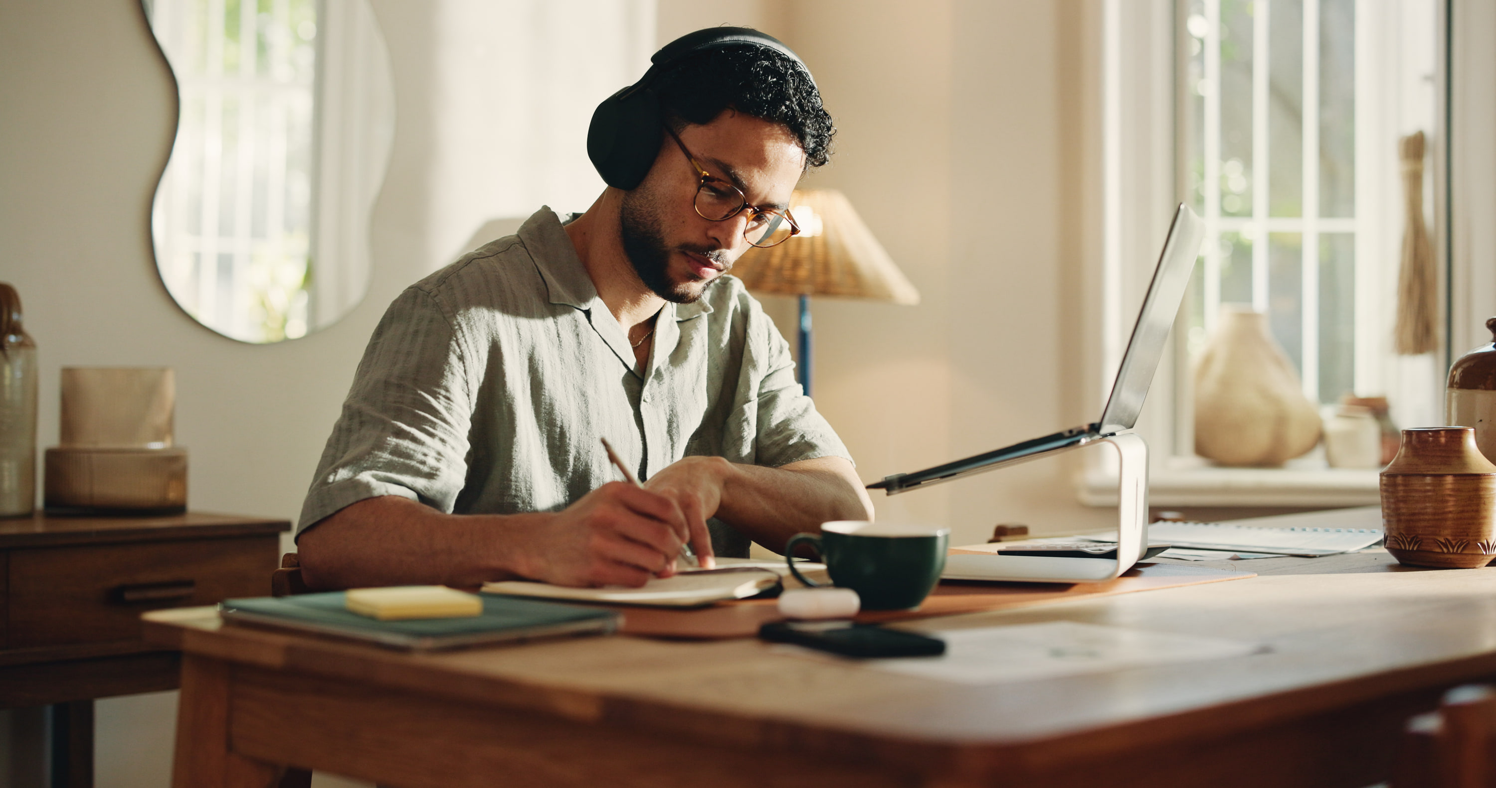 A man writing in a notebook at his table at home