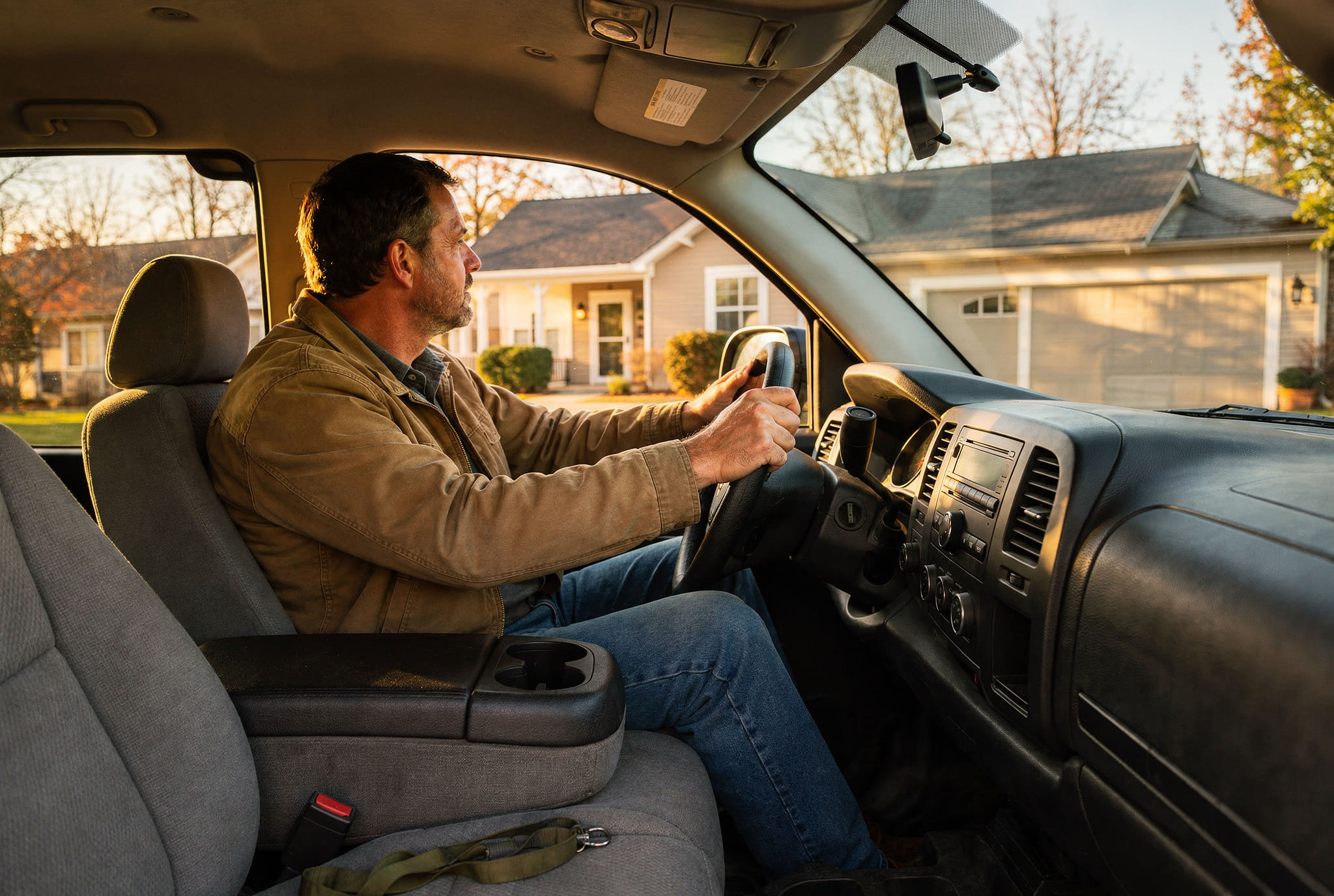 A man sitting in his truck in his own driveway after work