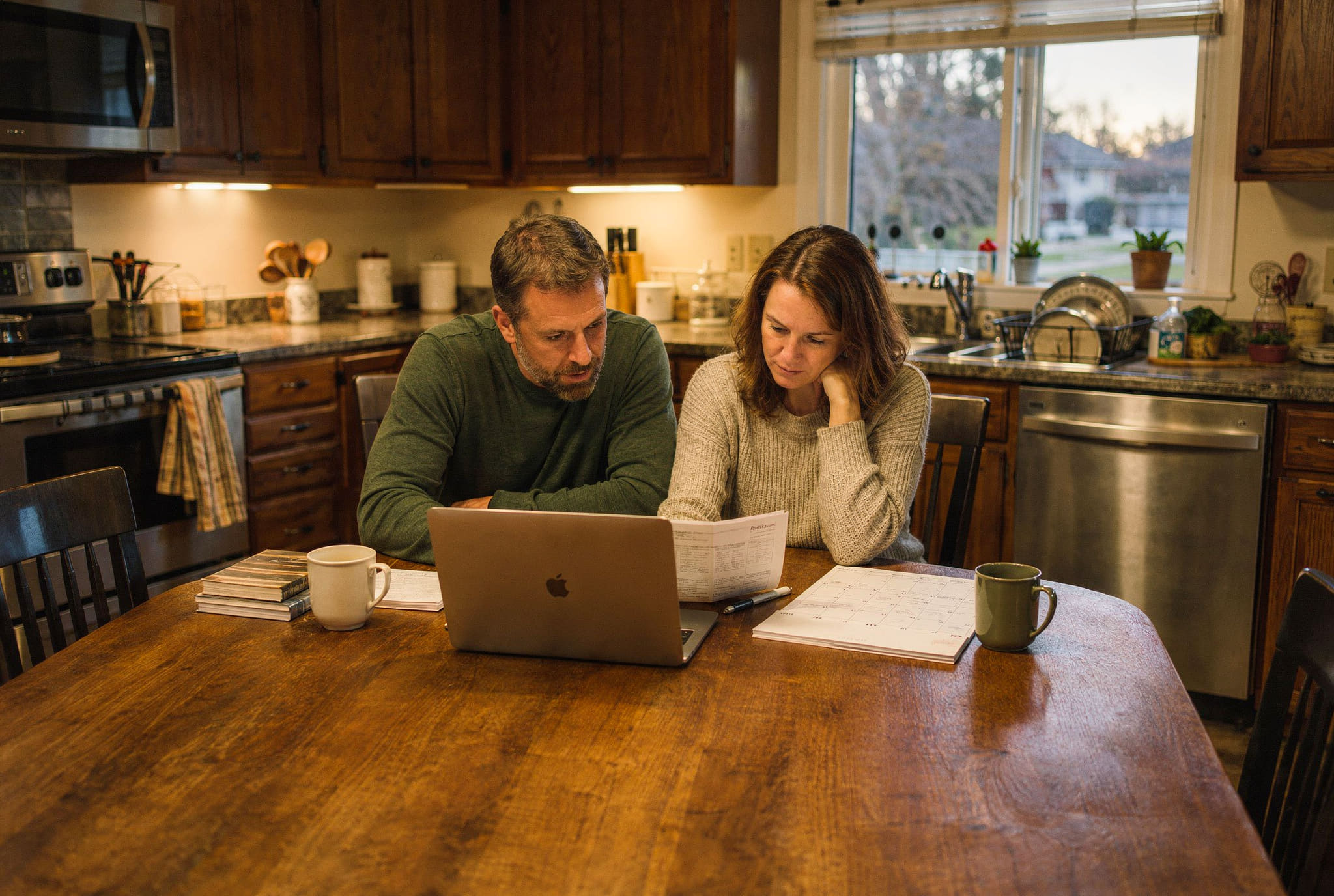 A couple at their kitchen table, working out the month