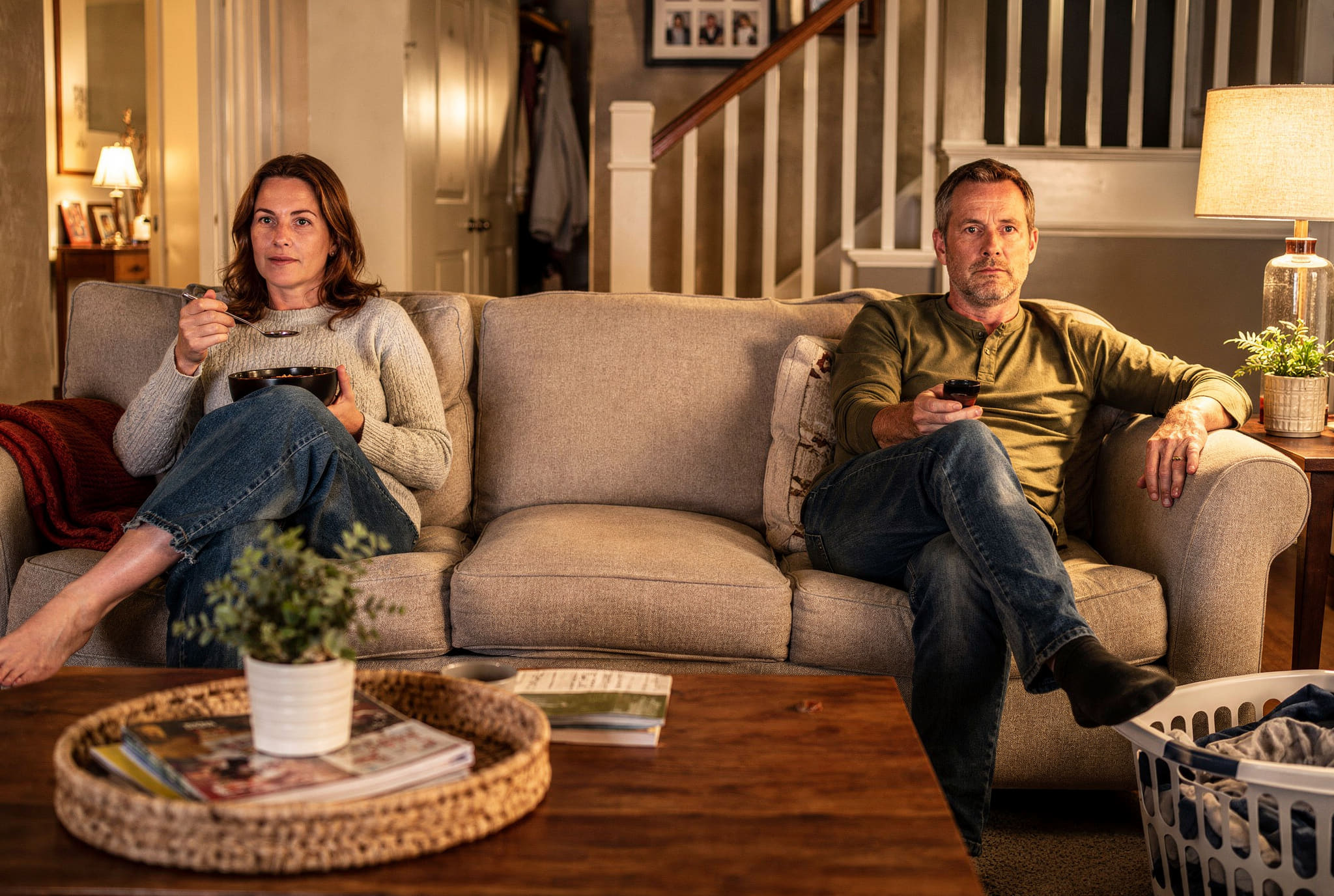 A couple at either end of their sofa in the evening