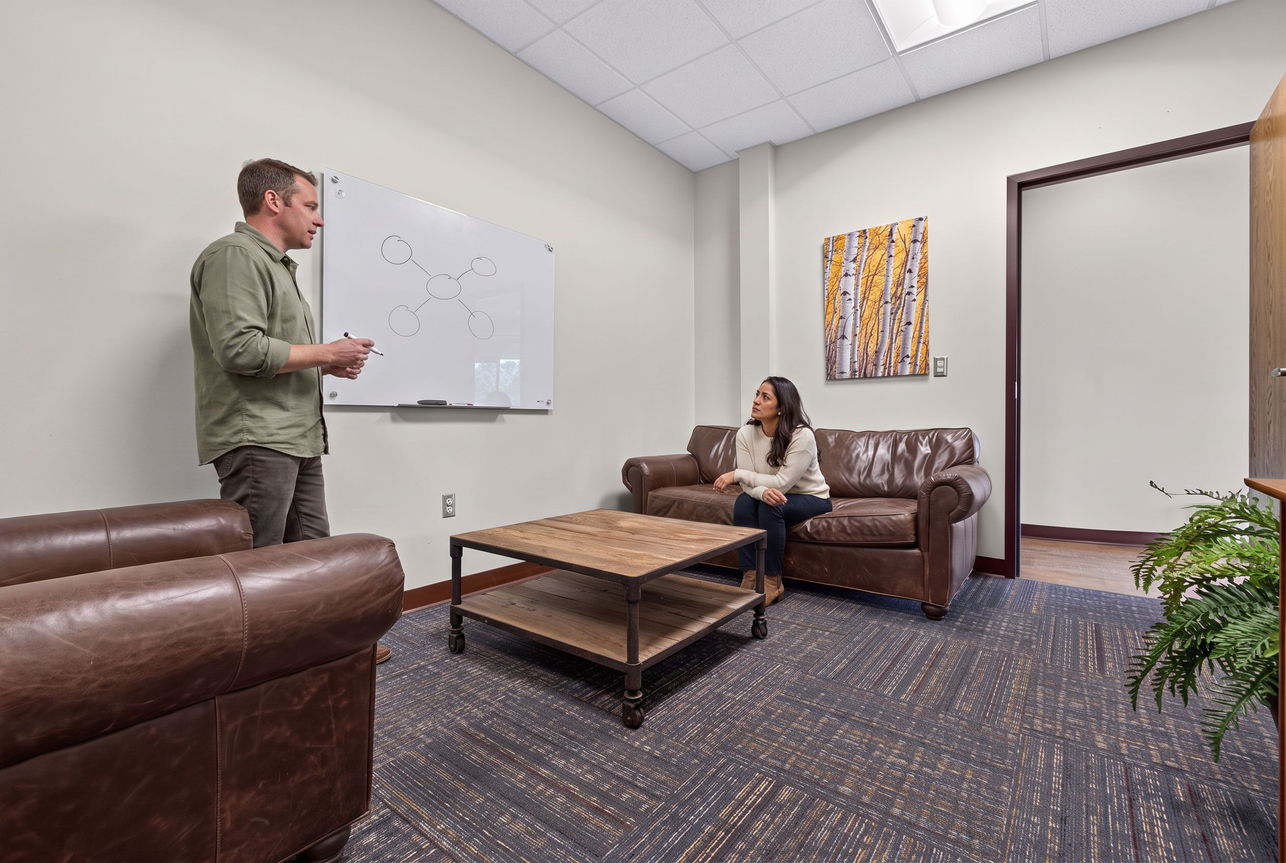 A counselor working through skills at the whiteboard with a client at Genesis