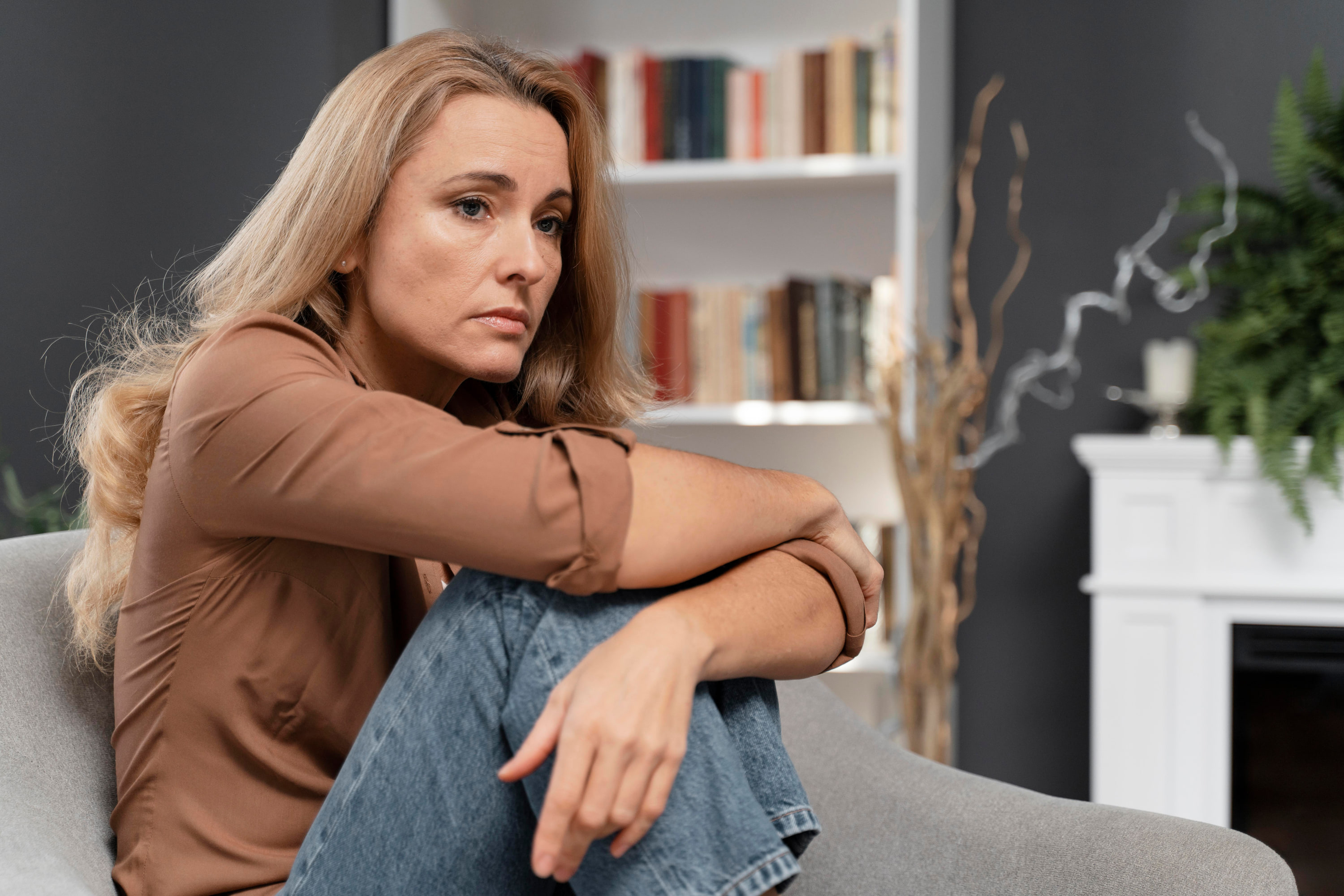 A woman sitting in an armchair with her knees drawn up